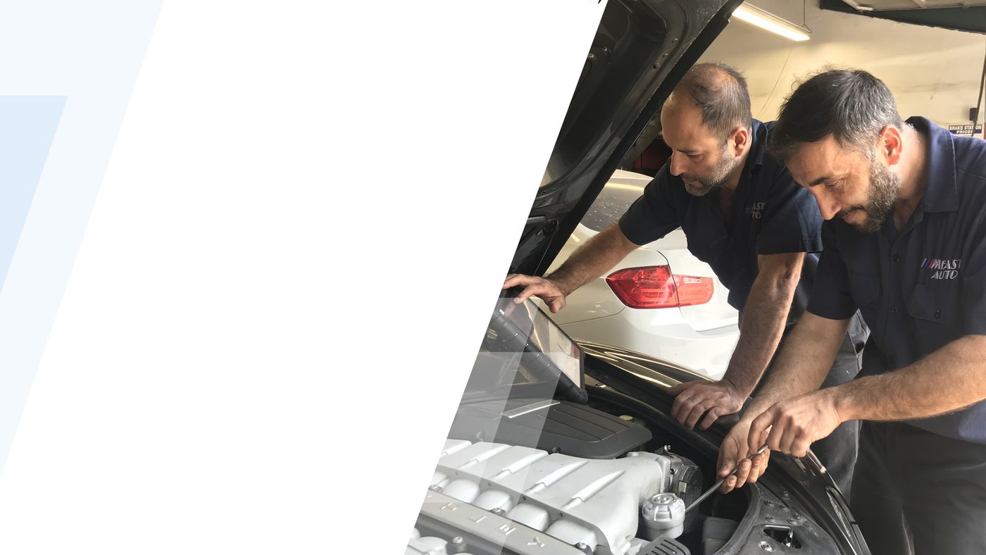 Two M Fast Auto mechanics working under the hood of a car in their Los Angeles shop